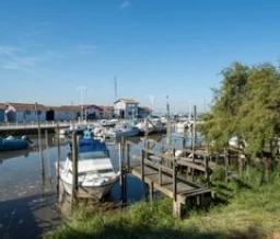 Port d’Arès avec bateaux de plaisance et cabanes, sous un ciel bleu – ZEcamping