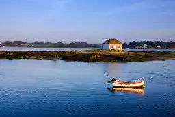 Paysage tranquille du Morbihan, avec un bateau amarré et une charmante maison sur une île.