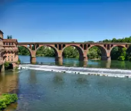 Pont de briques rouges traversant le Tarn dans un cadre naturel verdoyant - Zecamping