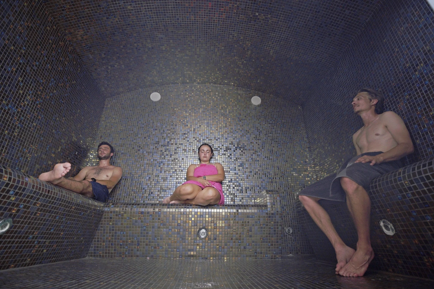 Hammam où trois personnes sont assises à l'intérieur, profitant de la chaleur et de l'humidité.