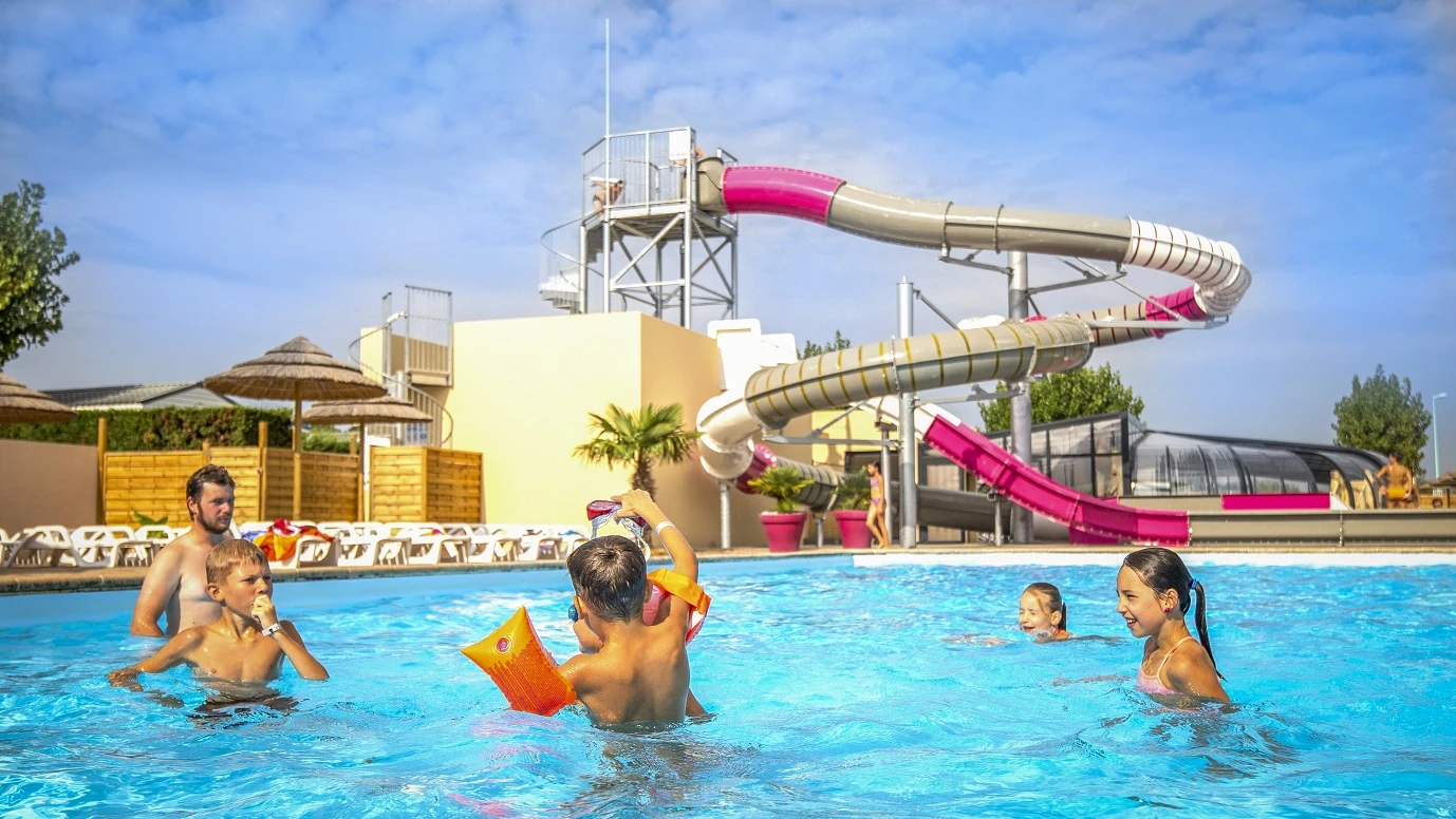  Sous un ciel ensoleillé, des vacanciers profitent d'une piscine aux eaux cristallines, entourée de transats et de parasols en chaume